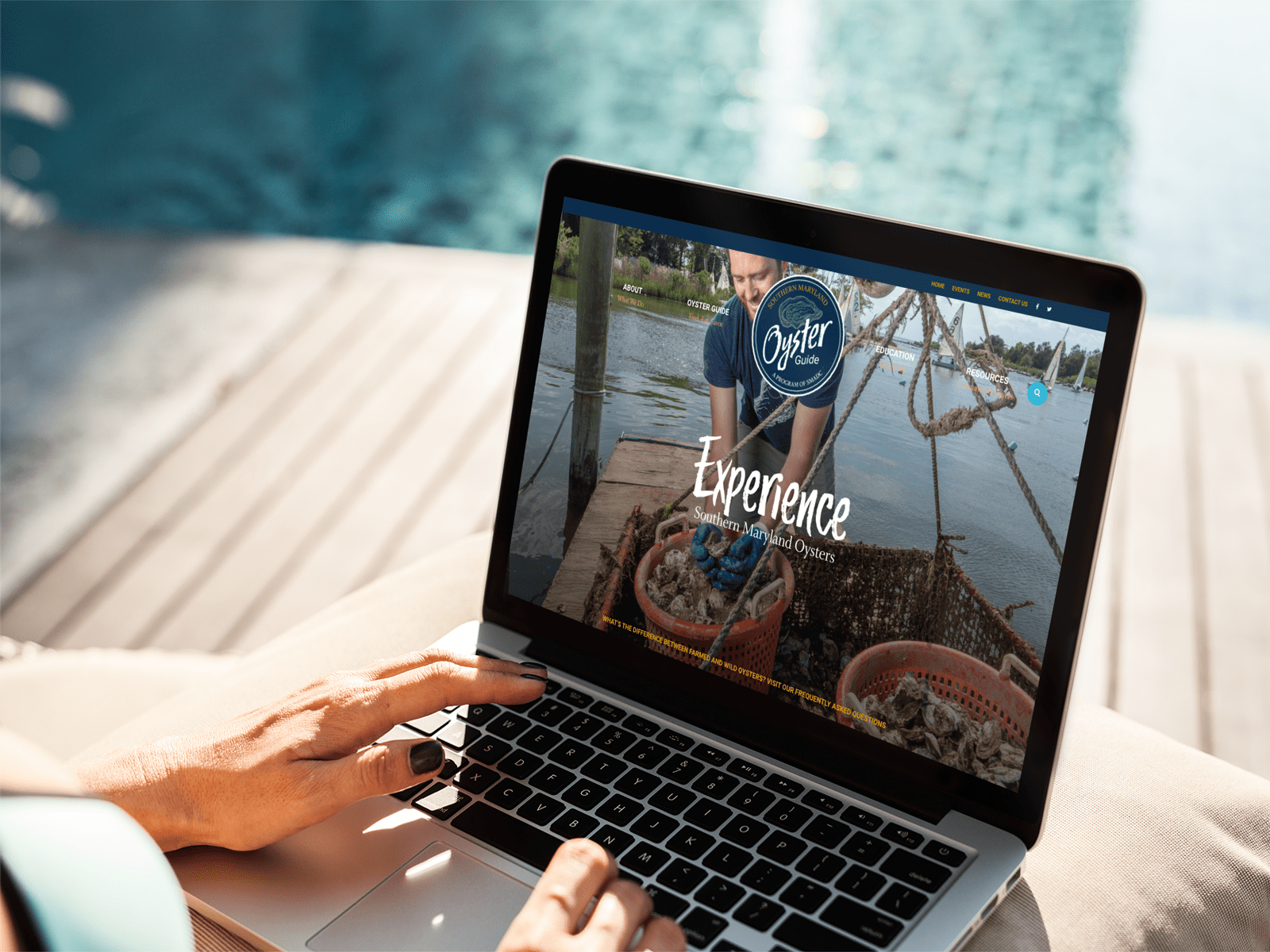 A person using a laptop by a swimming pool. The screen shows a webpage titled