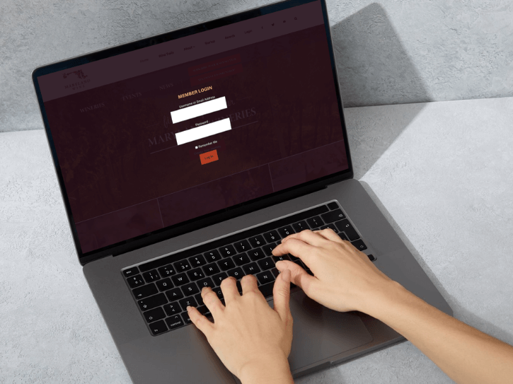 A person types on a laptop keyboard, logging in to a website with a
