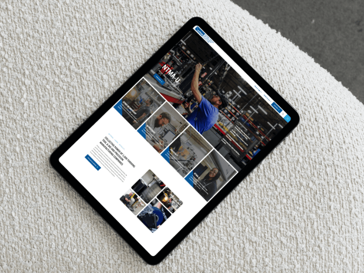 A tablet displaying a website with images of people working in a warehouse environment, placed on a textured white surface.